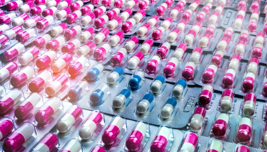 Closeup pink-white and blue-white antibiotics capsule pills in a blister pack. Probiotic while taking antibiotics - get rid of UTI without antibiotics