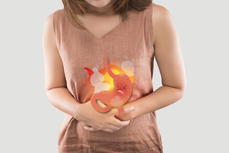 can gut bacteria cause acid reflux as a woman holds her stomach in pain